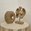 مجسمه رومیزی فرشته فلوت‌زن در کنار گلدان تک روی میز